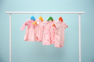 Baby clothes hanging on rack against color background