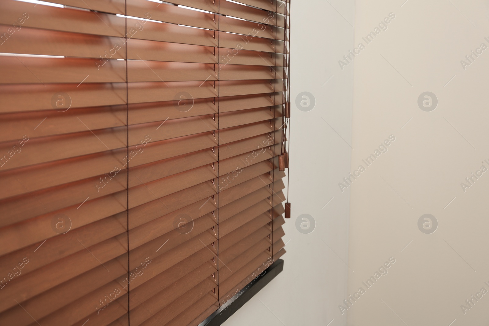 Photo of Modern window with closed stylish wooden blinds indoors. Space for text