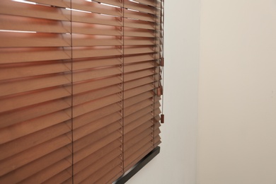 Photo of Modern window with closed stylish wooden blinds indoors. Space for text