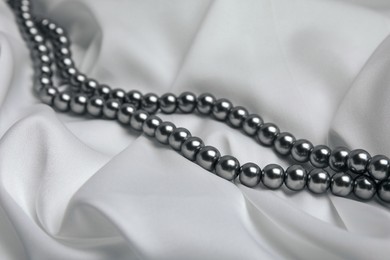 Beautiful pearls on white silk, closeup view