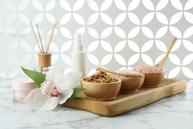 Beautiful composition with different spa products and orchid on white marble table