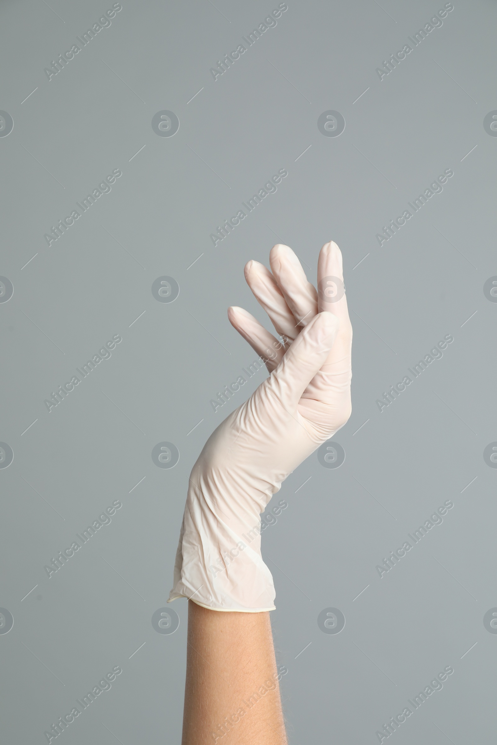 Photo of Doctor wearing medical gloves on grey background, closeup