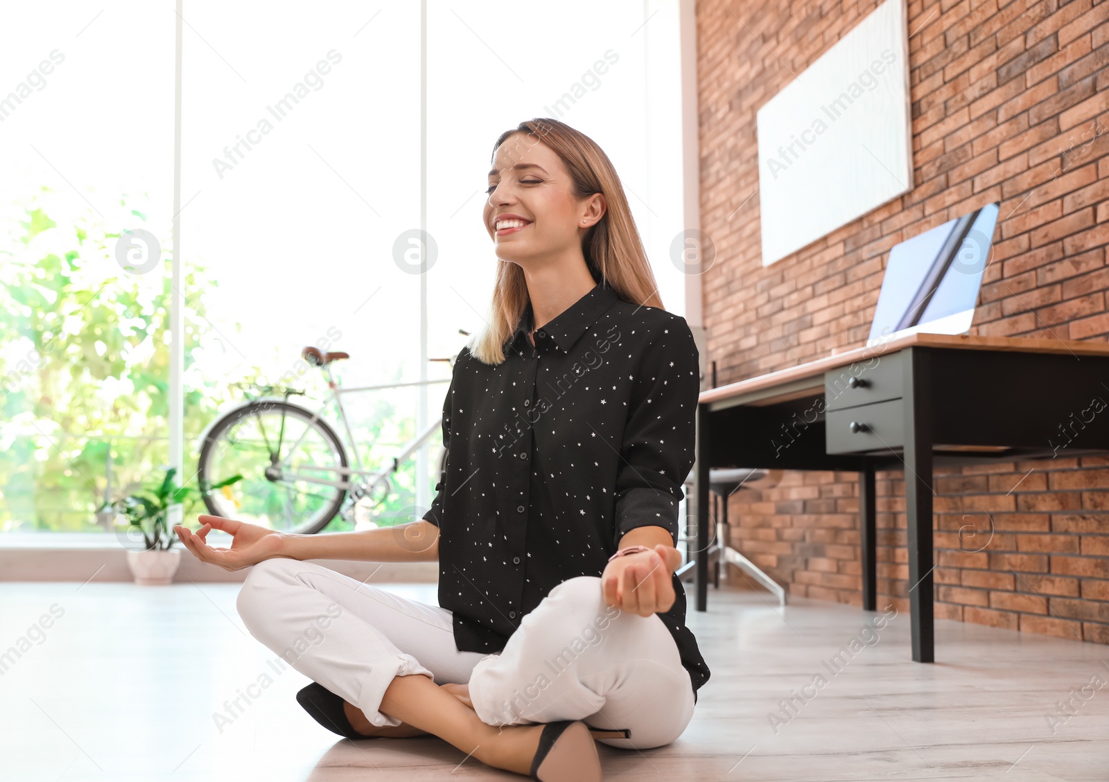 Photo of Young businessman doing yoga exercises in office. Workplace fitness