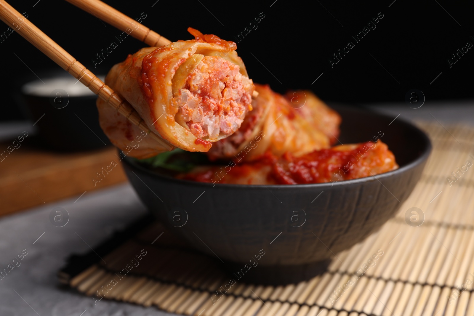 Photo of Taking delicious stuffed cabbage roll from bowl at table, closeup. Space for text