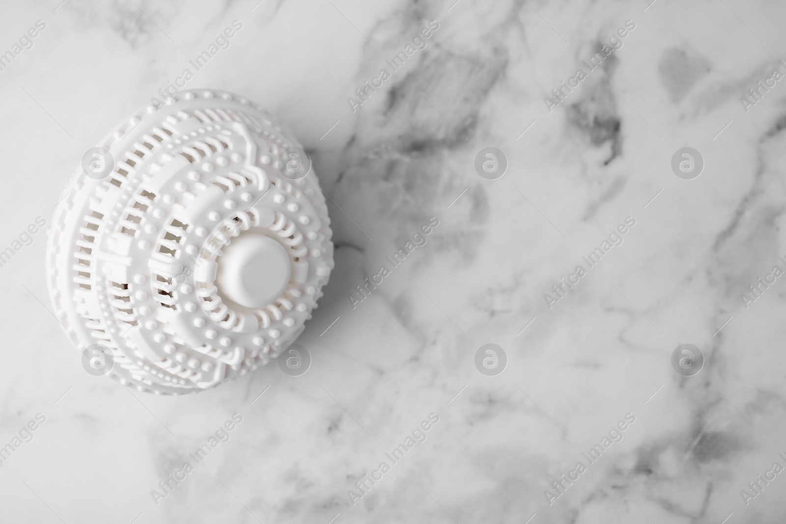 Photo of Laundry dryer ball on white marble table, top view. Space for text