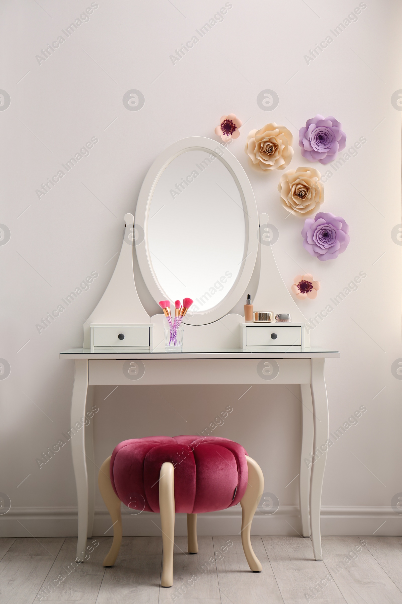 Photo of Stylish room interior with floral decor, dressing table and pouf