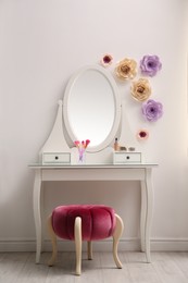 Stylish room interior with floral decor, dressing table and pouf