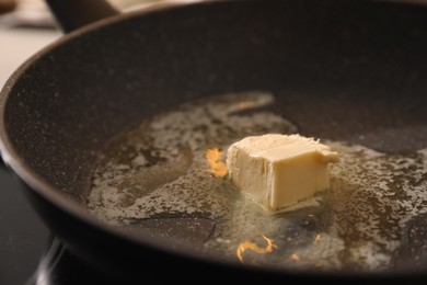 Photo of Frying pan with melted butter on stove, closeup