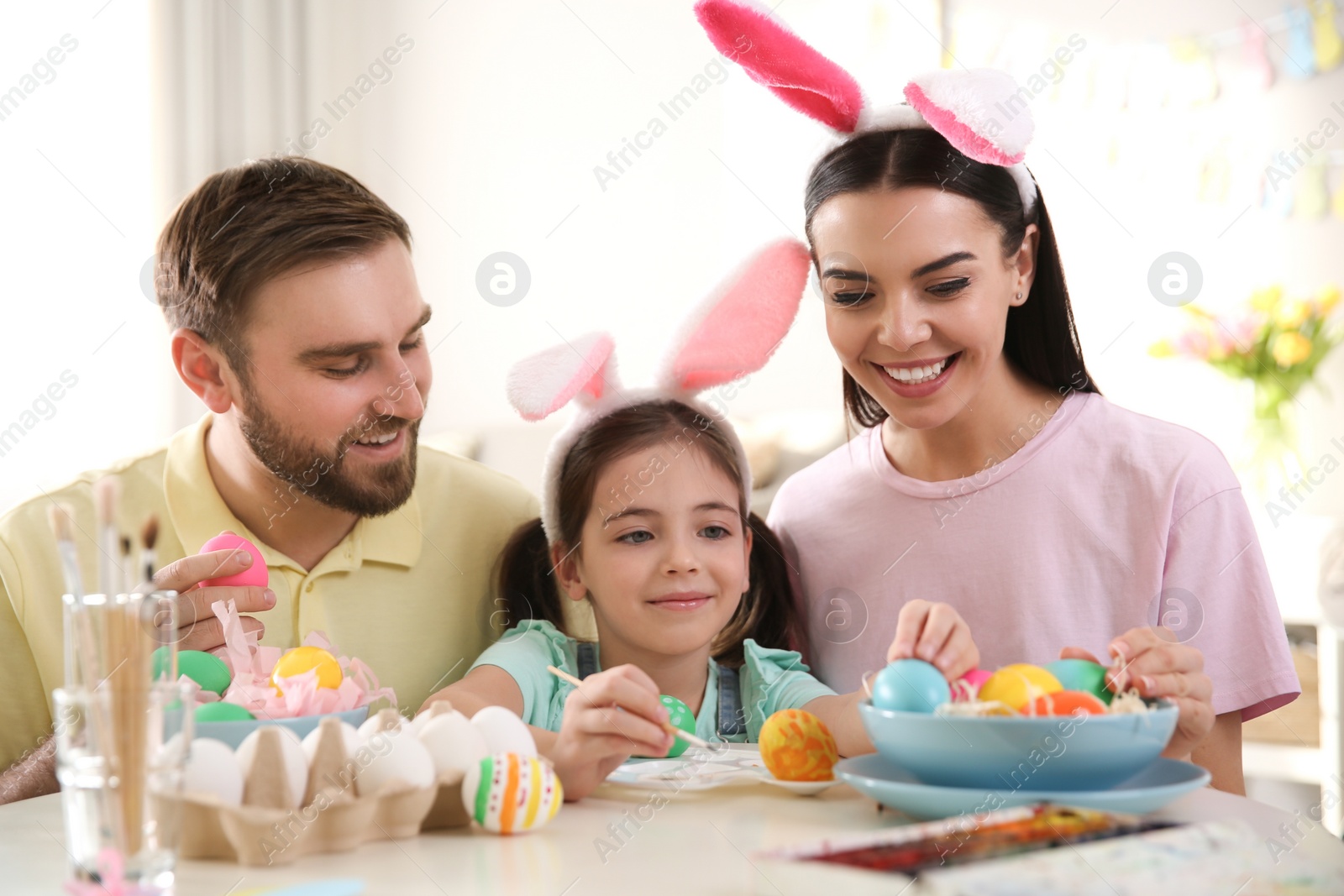 Photo of Happy family painting Easter eggs at table indoors