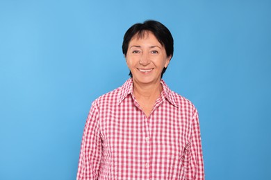 Portrait of smiling senior woman on light blue background