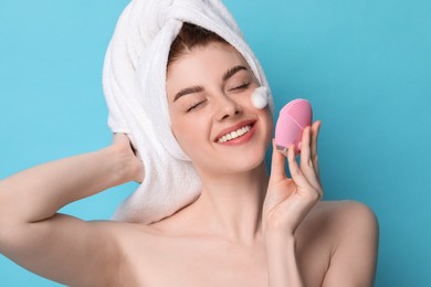 Photo of Young woman washing face with brush and cleansing foam on light blue background