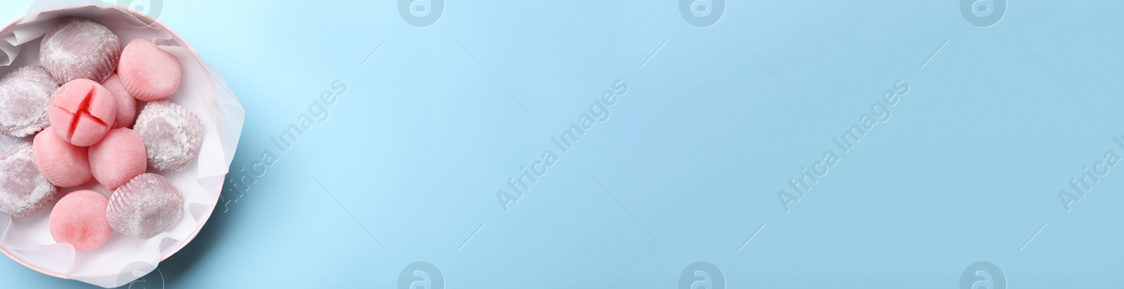 Photo of Many different delicious mochi in box on light blue background, top view with space for text. Traditional Japanese dessert