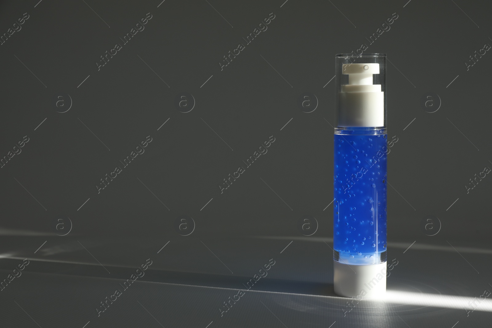 Photo of Bottle of cosmetic product on grey table. Space for text