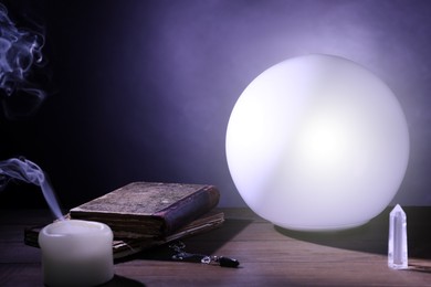 Photo of Prediction ball, books, stones and candle on table in darkness