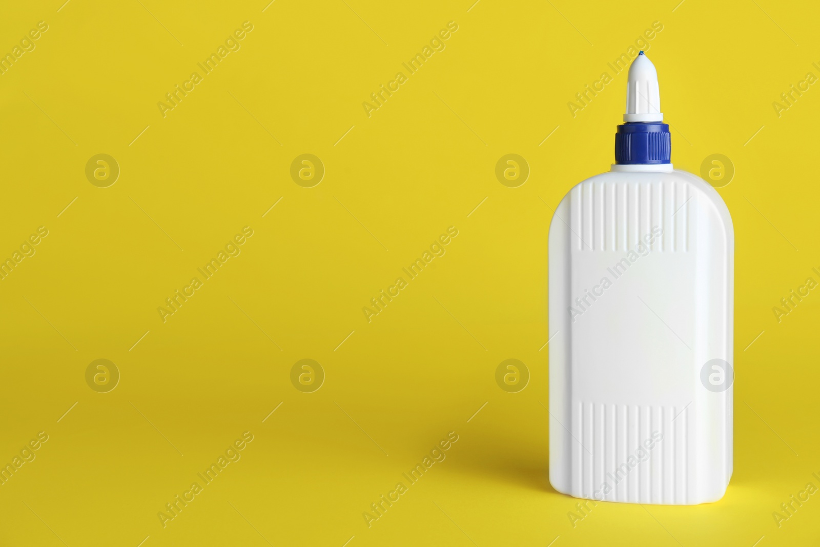 Photo of Bottle of glue on yellow background, space for text