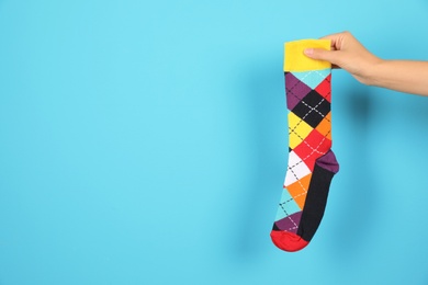 Woman holding bright sock and space for design on color background