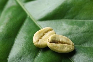 Photo of Green coffee beans on fresh leaf, closeup