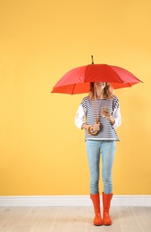 Woman with red umbrella near color wall