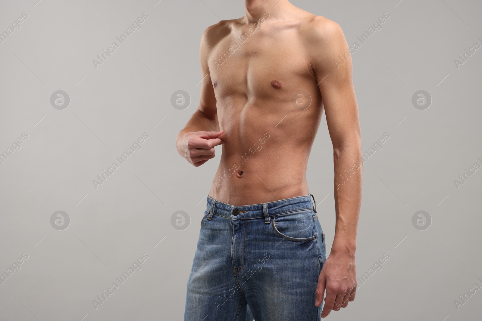 Photo of Shirtless man with slim body on grey background, closeup