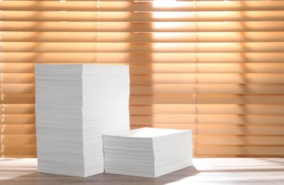 Photo of Stacks of paper sheets on wooden table. Space for text