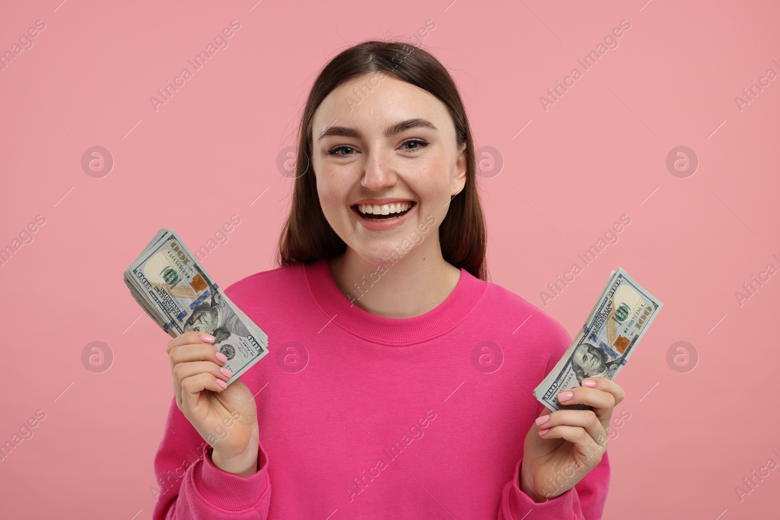 Photo of Happy woman with dollar banknotes on pink background