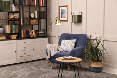 Photo of Cozy home library interior with collection of different books on shelves and comfortable place for reading