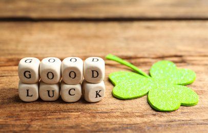Photo of Cubes with phrase GOOD LUCK and clover leaf on wooden table