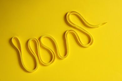 Photo of Shoe lace on yellow background, top view