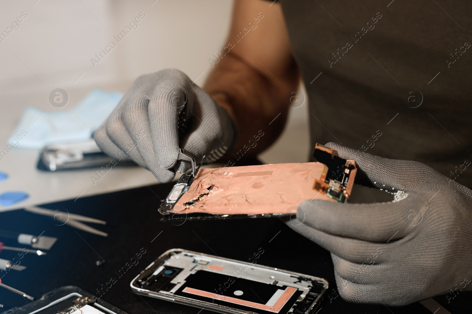 Photo of Technician repairing broken smartphone at table, closeup