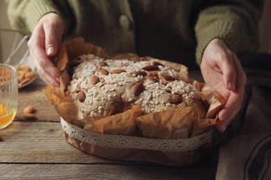 Photo of Woman with delicious Italian Easter dove cake (traditional Colomba di Pasqua) at wooden table, closeup