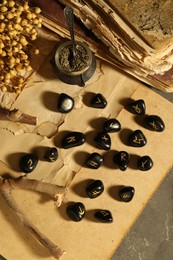 Photo of Many black rune stones, dried flowers and old books on grey table, flat lay