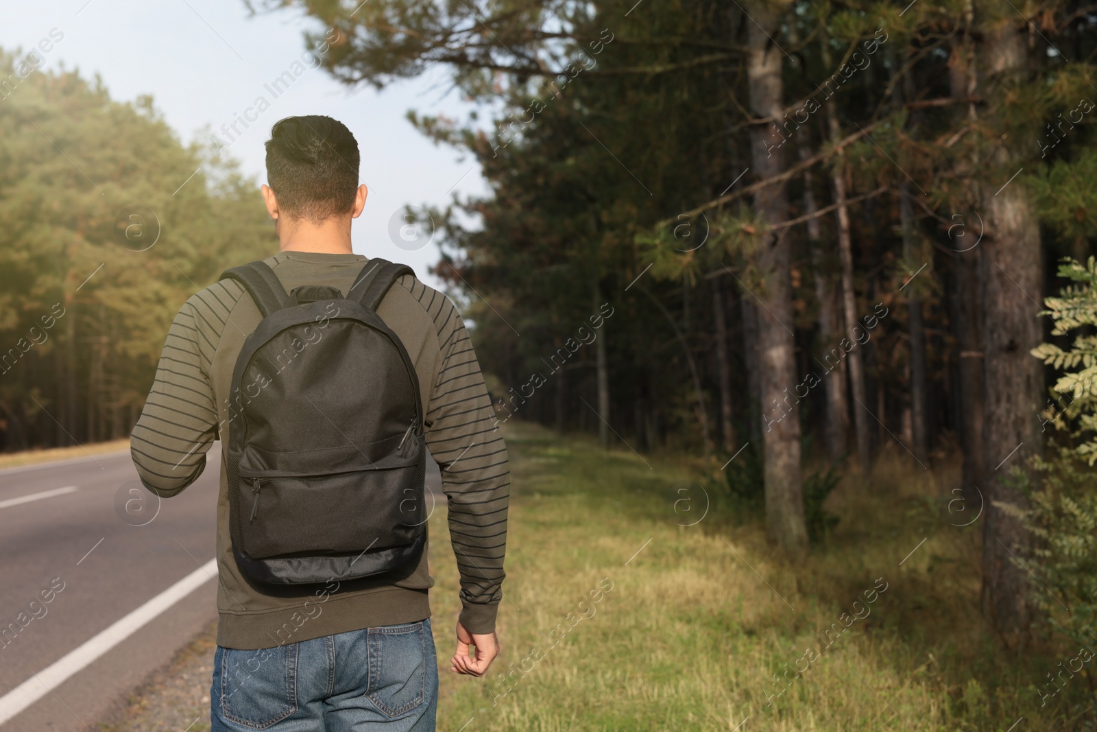 Photo of Man with backpack on road near forest, back view