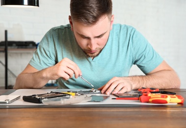 Technician repairing mobile phone at table in workshop