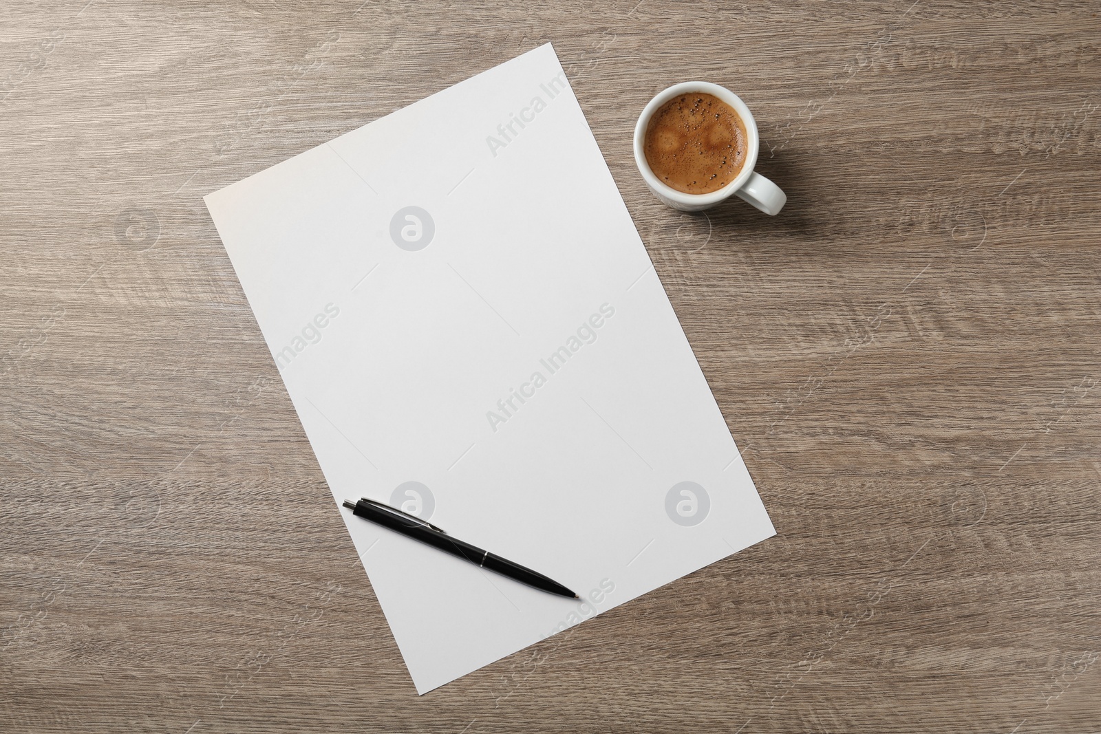 Photo of Blank paper sheet, pen and cup of coffee on wooden table, flat lay. Space for text