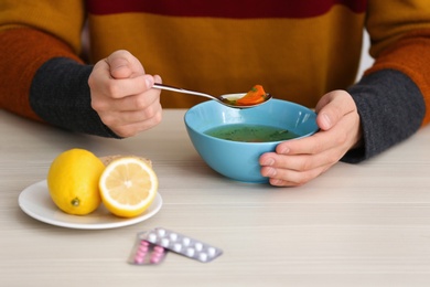 Sick young man eating soup to cure flu at table