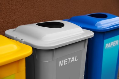 Photo of Many color recycling bins near brown wall, closeup