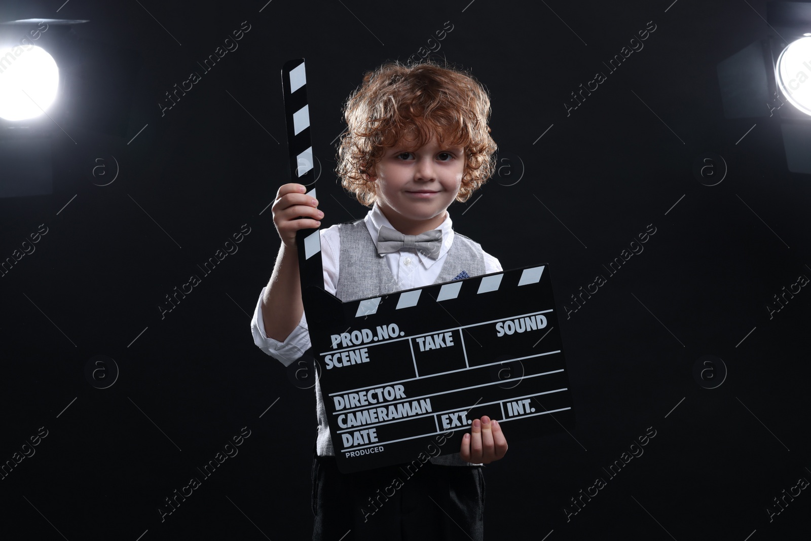 Photo of Cute boy with clapperboard on stage. Little actor