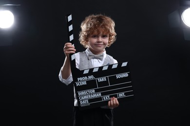 Photo of Cute boy with clapperboard on stage. Little actor