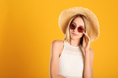 Photo of Beautiful woman in stylish sunglasses on yellow background. Space for text