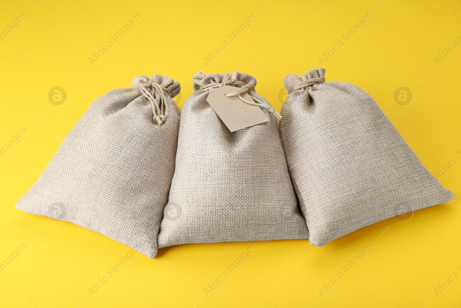 Photo of Three tied burlap bags on yellow background