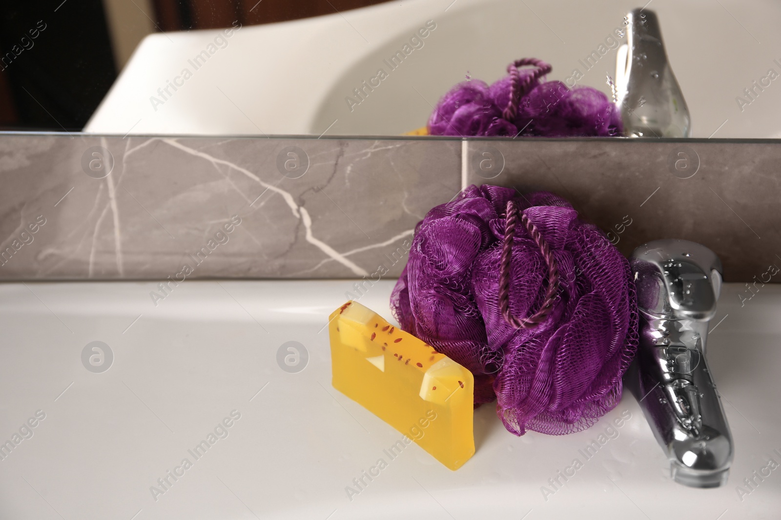 Photo of Purple shower puff and soap on sink in bathroom, space for text