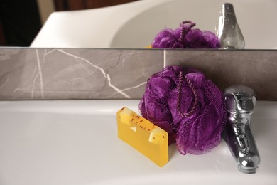 Purple shower puff and soap on sink in bathroom, space for text