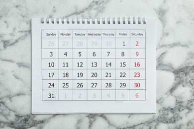 Photo of Paper calendar on marble background, top view