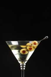 Photo of Martini cocktail with olives on dark background, space for text