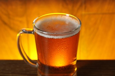 Photo of Mug with fresh beer on table against color background, closeup