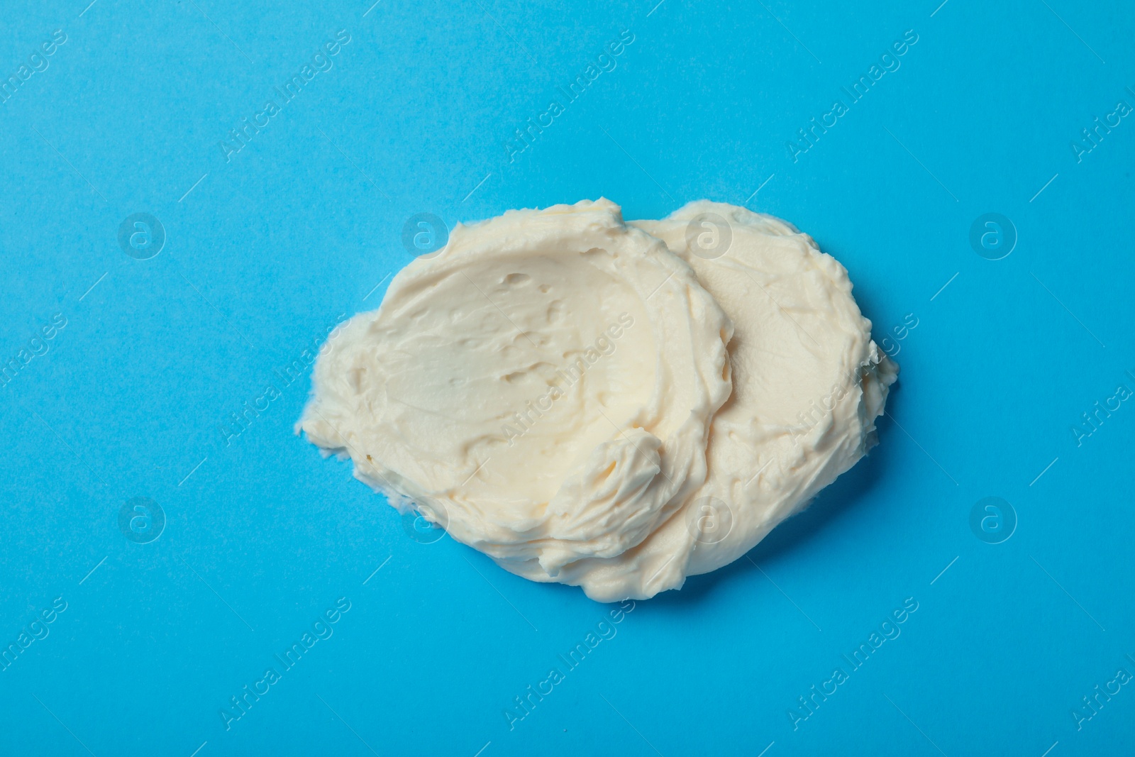 Photo of Smear of delicious cream cheese on light blue background, top view