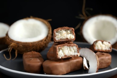 Photo of Delicious milk chocolate candy bars with coconut filling on grey plate, closeup