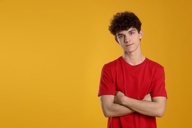 Portrait of cute teenage boy on orange background. Space for text