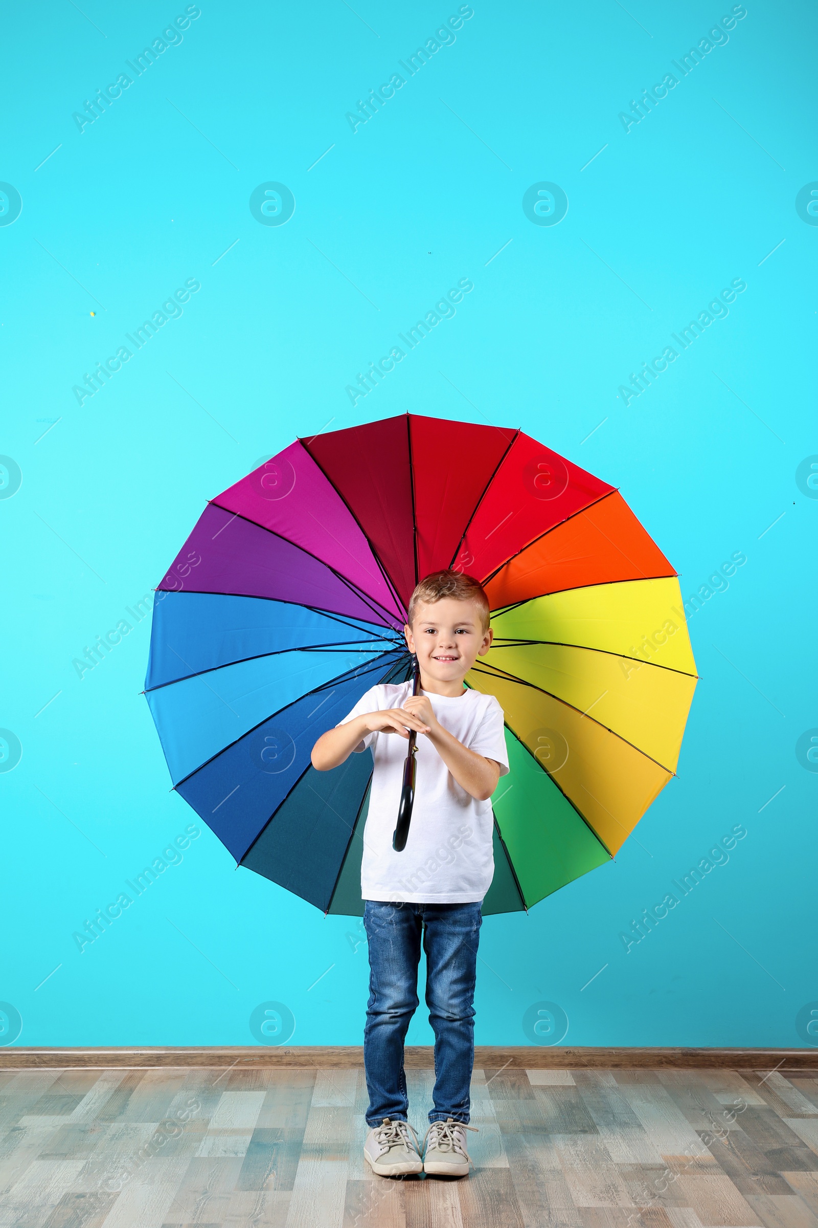 Photo of Little boy with rainbow umbrella near color wall