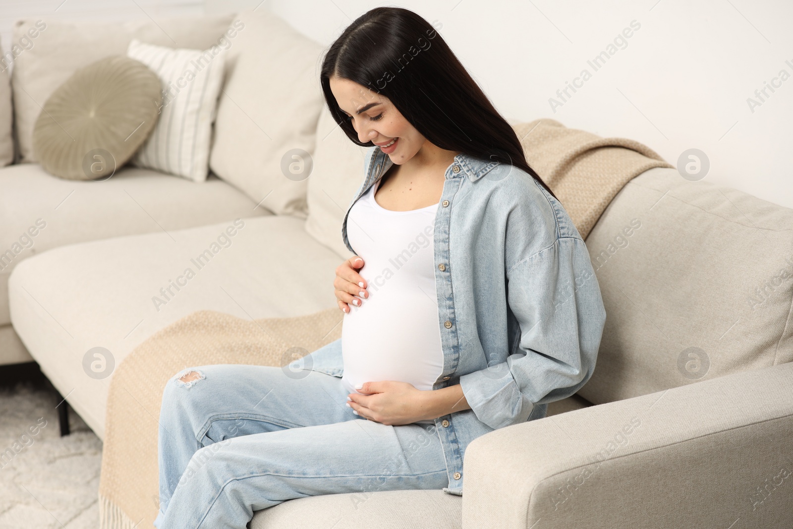 Photo of Happy pregnant woman on sofa at home